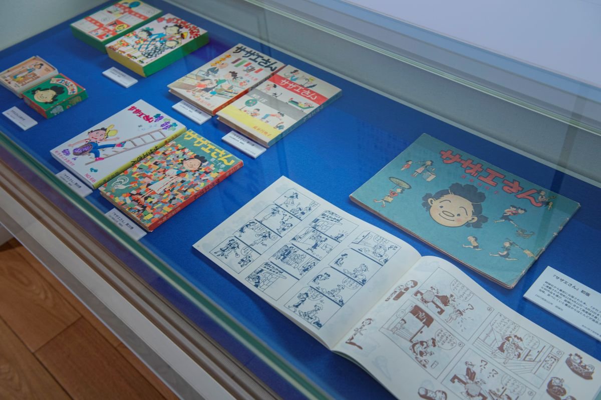 2階の常設展示室には、長谷川町子一家が設立した「姉妹社」から出版された『サザエさん 第1巻』の初版本をはじめ、町子の生涯を作品とともに辿る資料が集まります。B5判の横綴じは書店で扱いにくく返品が多かったものの、第2巻をB6縦判で出版したところ大ヒットとなりました。