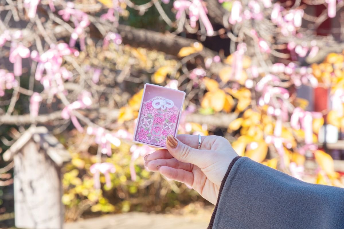 桜の刺繍が施されたレース守（1500円）や、縁結びを願って河津桜に結ぶ花帯（500円）の授与など、多くの方に参拝していただきたいという思いからさまざまな取り組みを行っています。